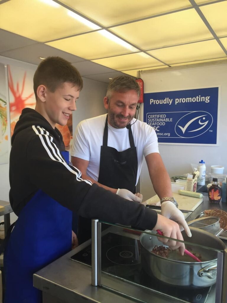 Kevin Dalgleish showing a youngster how to cook min